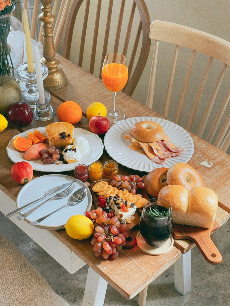 Mesa de café da manhã farta, com frutas frescas, pães e bebidas dispostos para servir