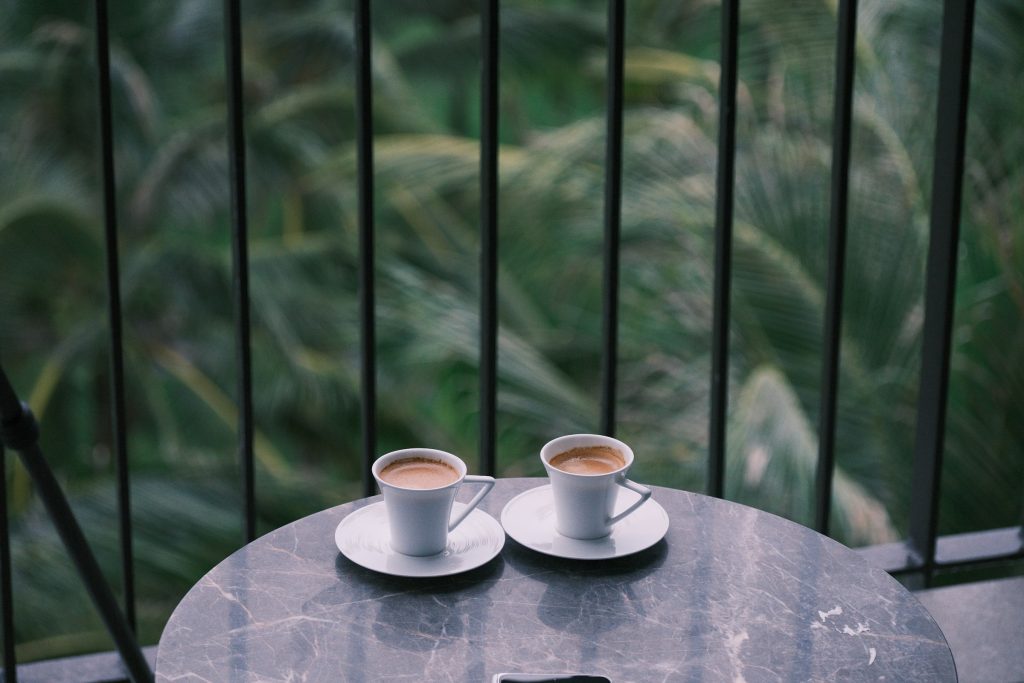 Duas xícaras de café sobre mesinha de varanda no começo da manhã