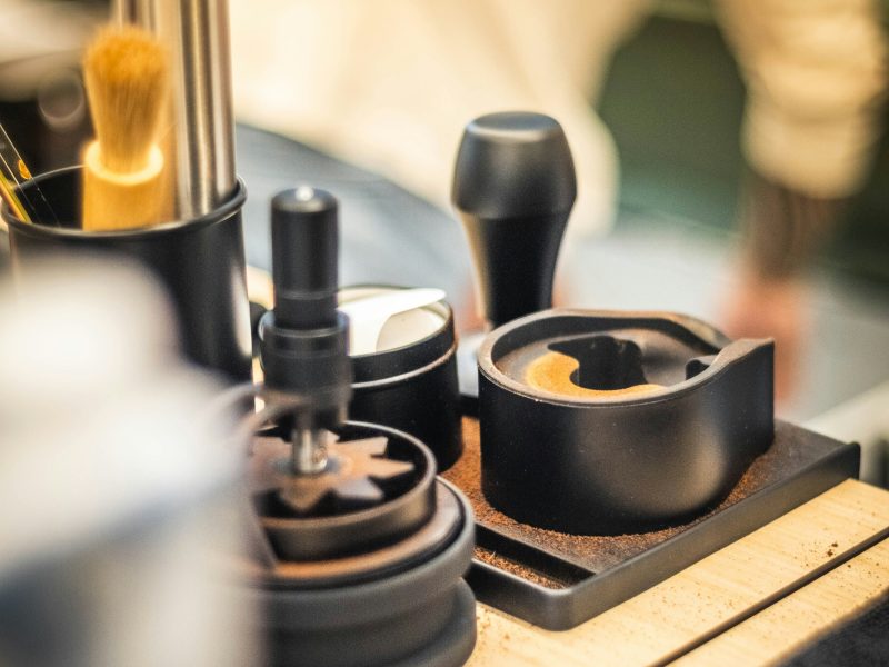 Utensílios de barista e grãos de café sobre balcão de madeira na cafeteria