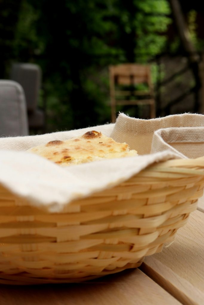 Cesta de palha com pães artesanais sobre mesa de madeira ao ar livre