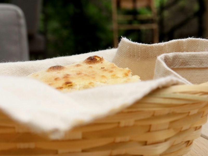 Cesta de palha com pães artesanais sobre mesa de madeira ao ar livre