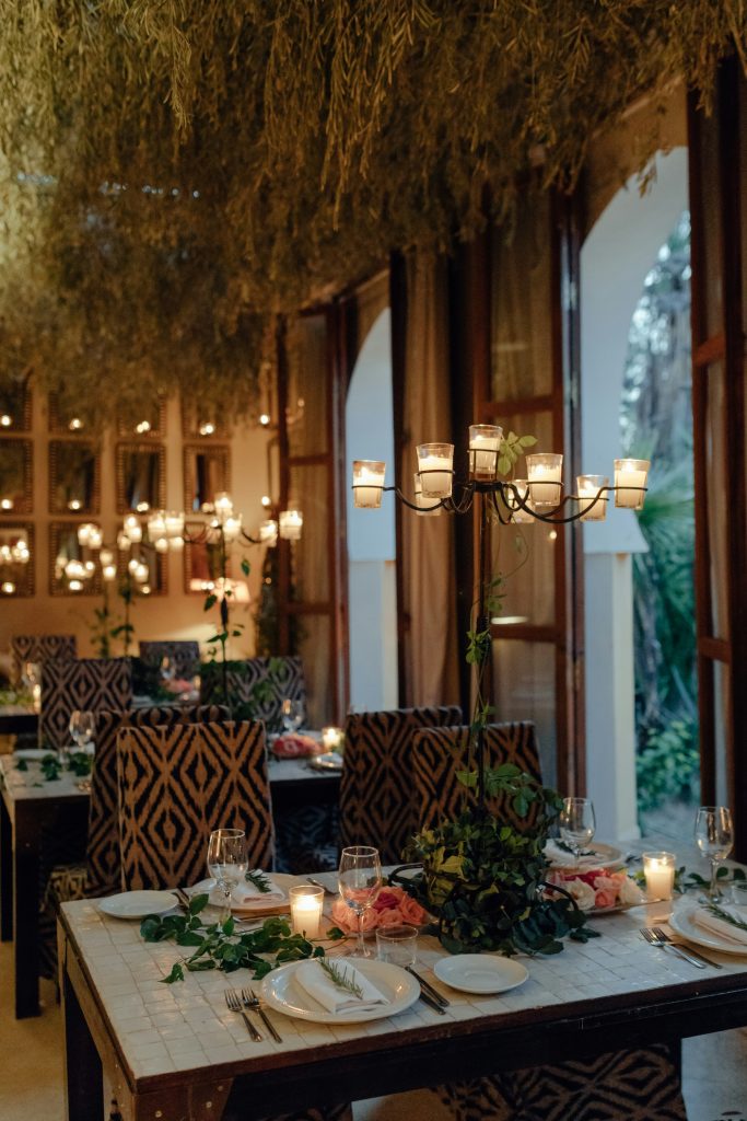 Mesa de jantar servida à luz de velas, com pratos e taças em ambiente de penumbra quente