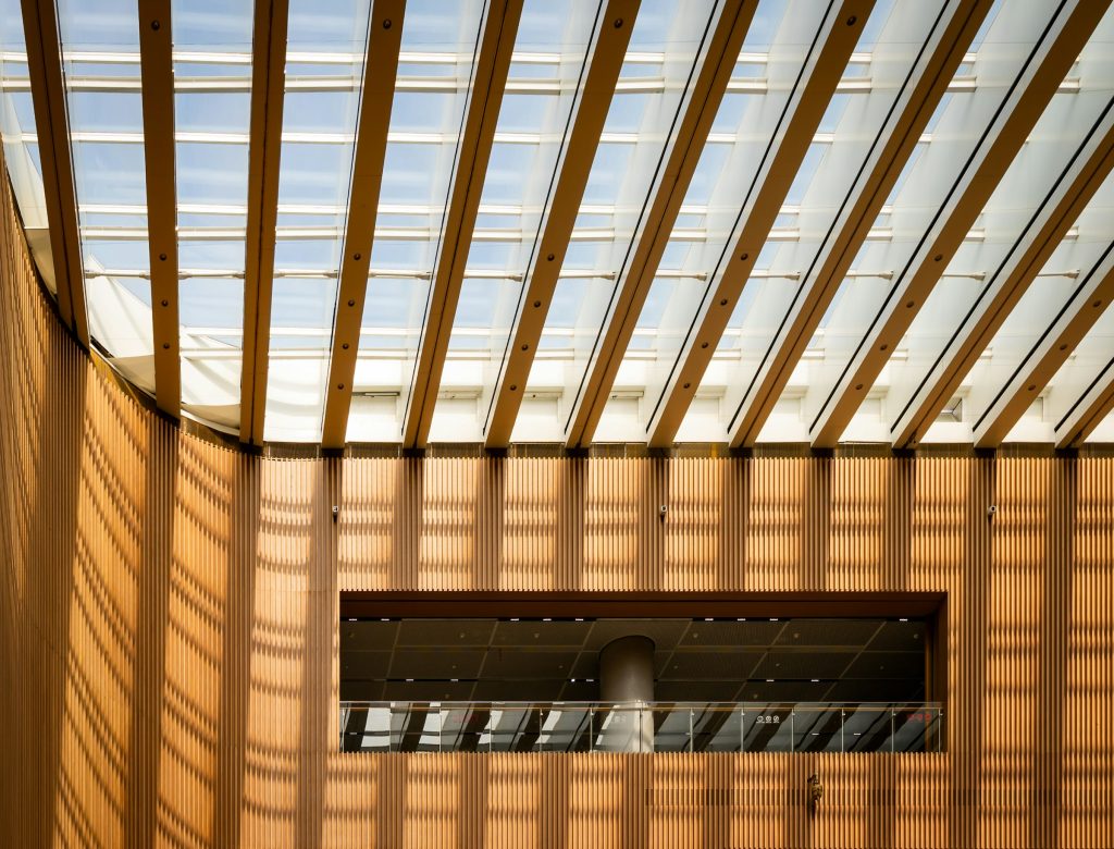 Interior minimalista com forro ripado de madeira e claraboia derramando luz natural sobre as paredes