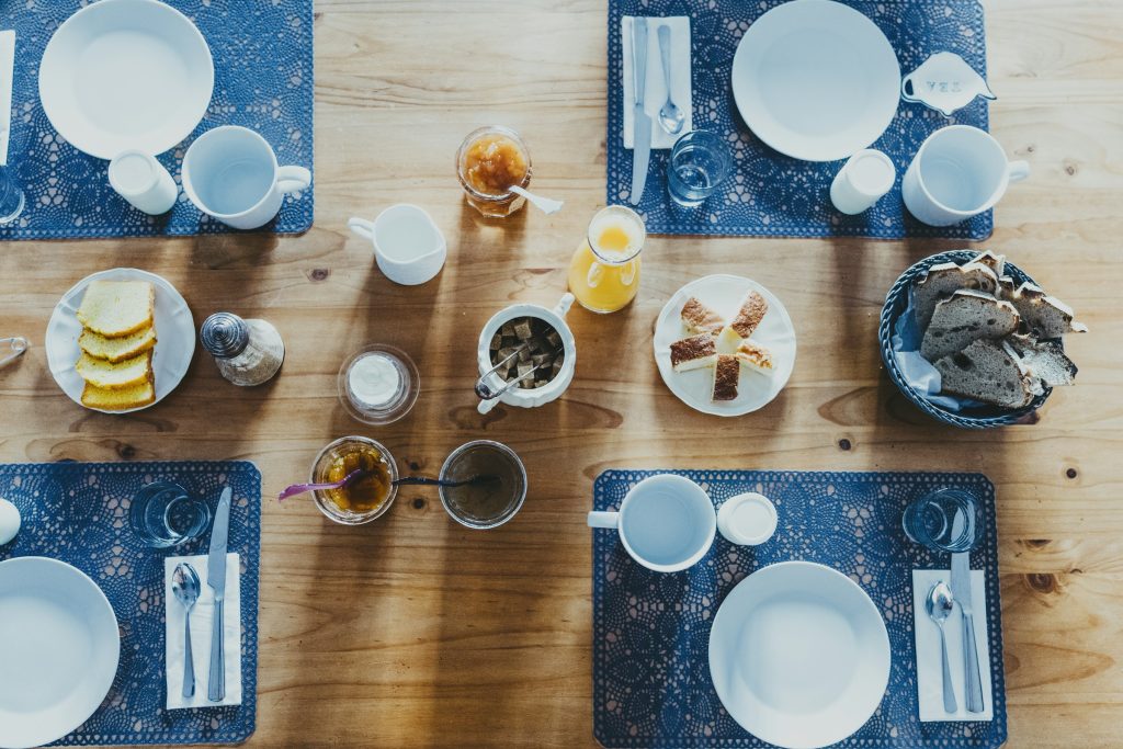 Mesa de madeira maciça coberta de pratos e tigelas com comida caseira e café