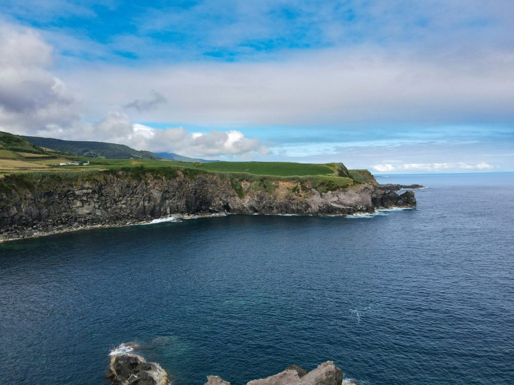 Encosta verde descendo ate o mar azul profundo vista de um mirante na costa