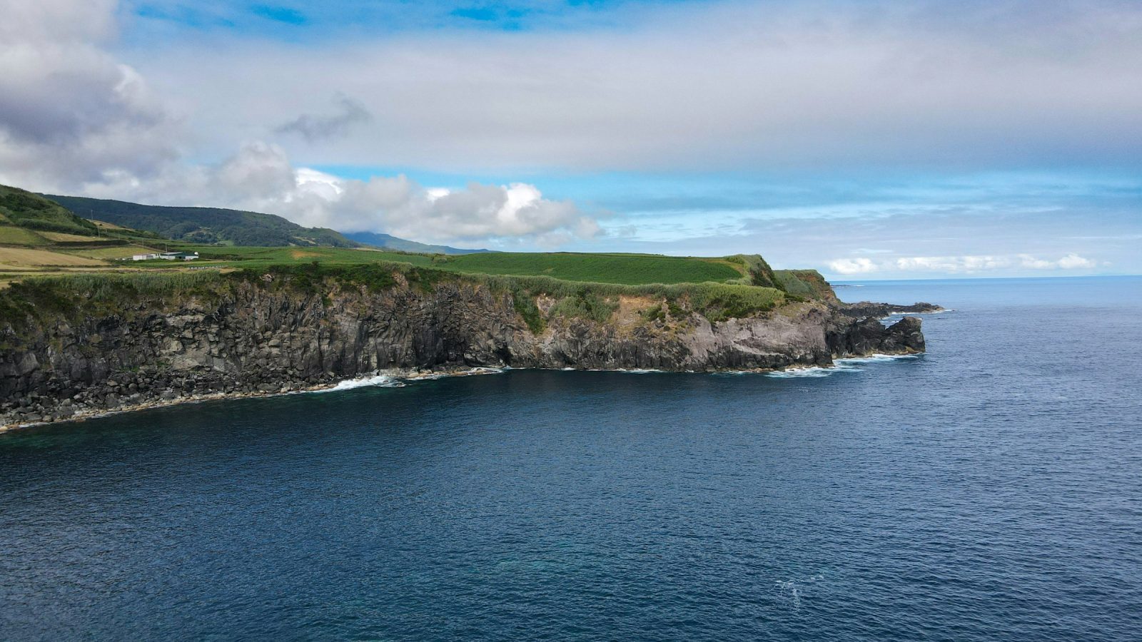 Encosta verde descendo ate o mar azul profundo vista de um mirante na costa