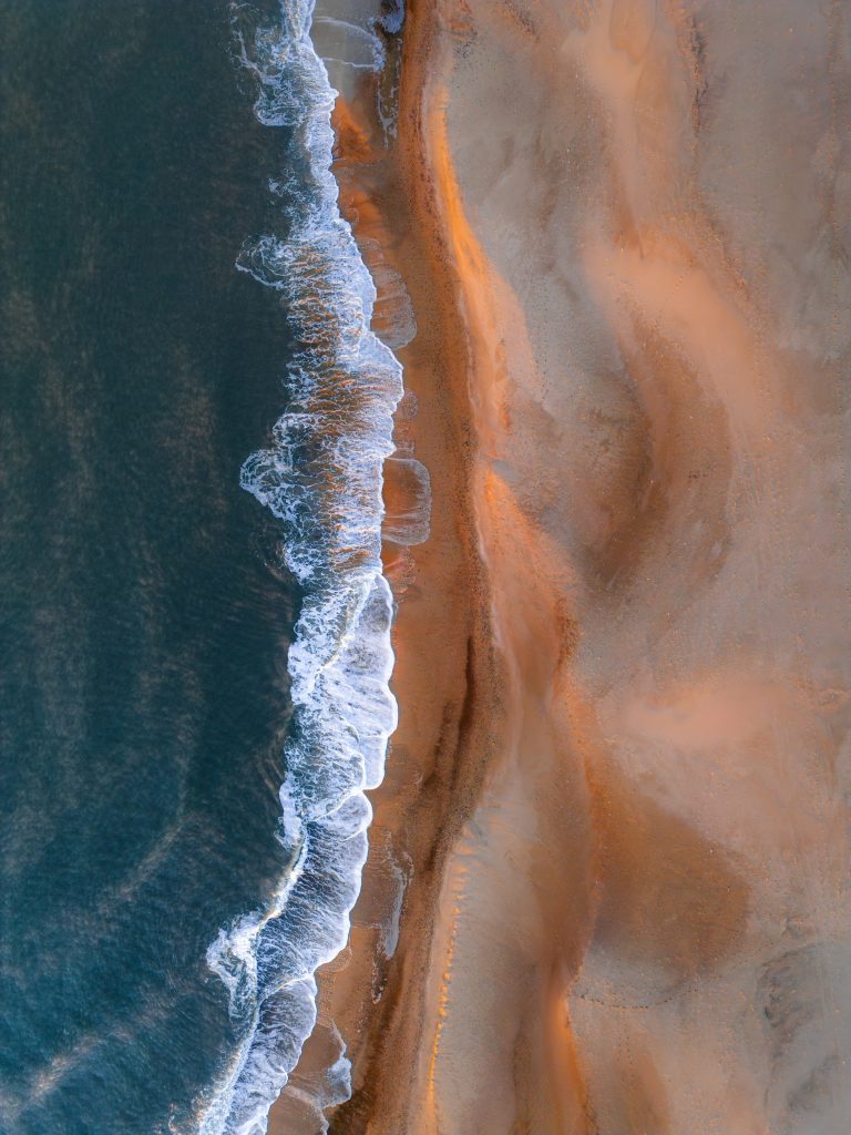 Ondas suaves alcancando a areia de uma praia deserta de mar aberto