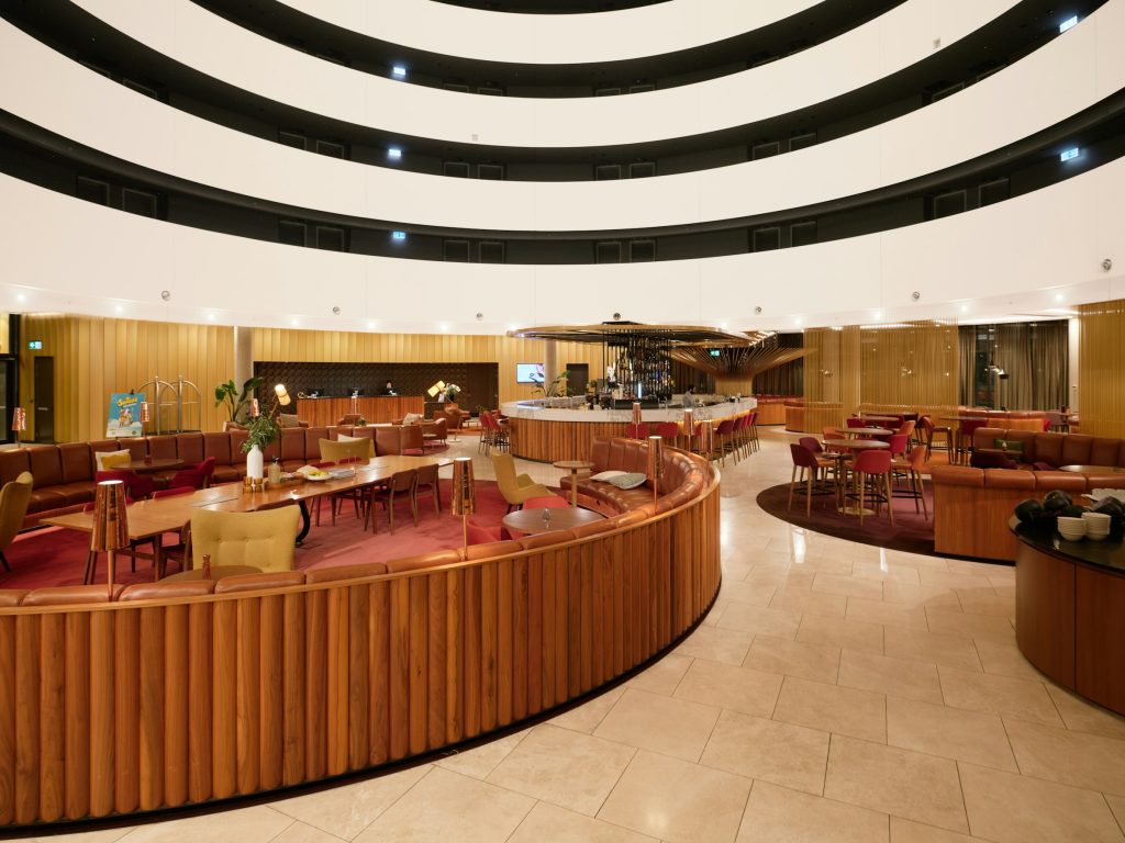 Interior de recepção com paredes curvas de ripas de madeira e iluminação quente