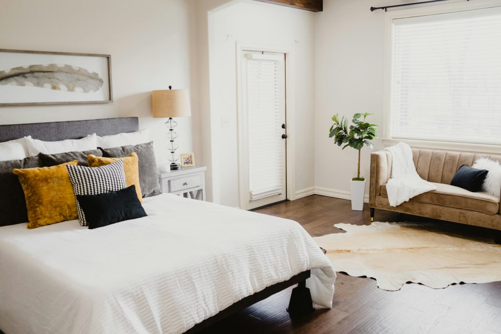 Cama com roupa de cama branca amassada ao lado de porta de madeira pintada de branco